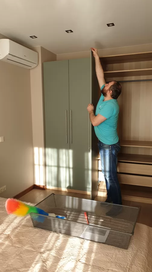 Мужчина на час сборщик мебели занимается регулеровкой двери в шкафу: мастер на час в Риге